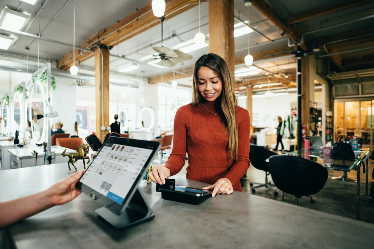 Une commerçante encaisse un client à la caisse de sa boutique.